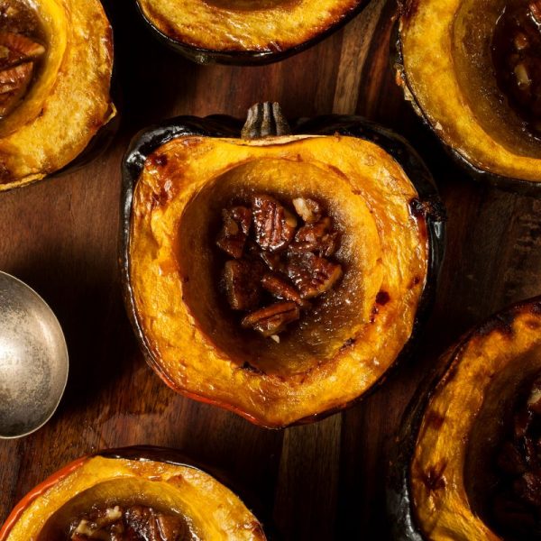 savoury roasted organic acorn winter squash cut in halve on a wooden board.