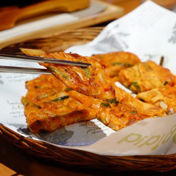 close up of kimchi pizza being served with tongs