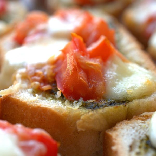 close-up of bruschetta - break, pesto, tomato, and mozzarella cheese