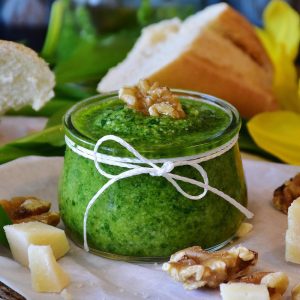 a container of pesto with walnut and chunks of parmesan cheese placed around the container