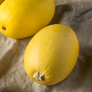 Organic spaghetti winter quash with bright yellow skin on a cream coloured bag