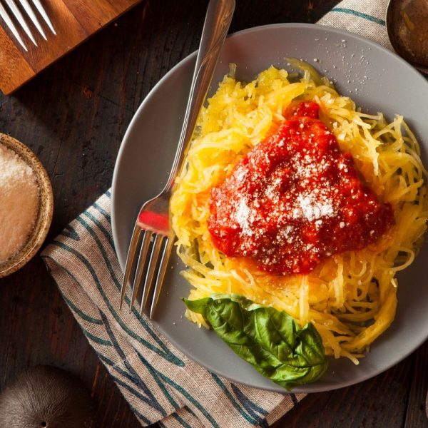 An appetizing plate of spaghetti squash noodles on a grey plate with red pasta sauce