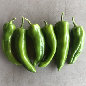 a group of 6 green carmen peppers, the pointy variety.